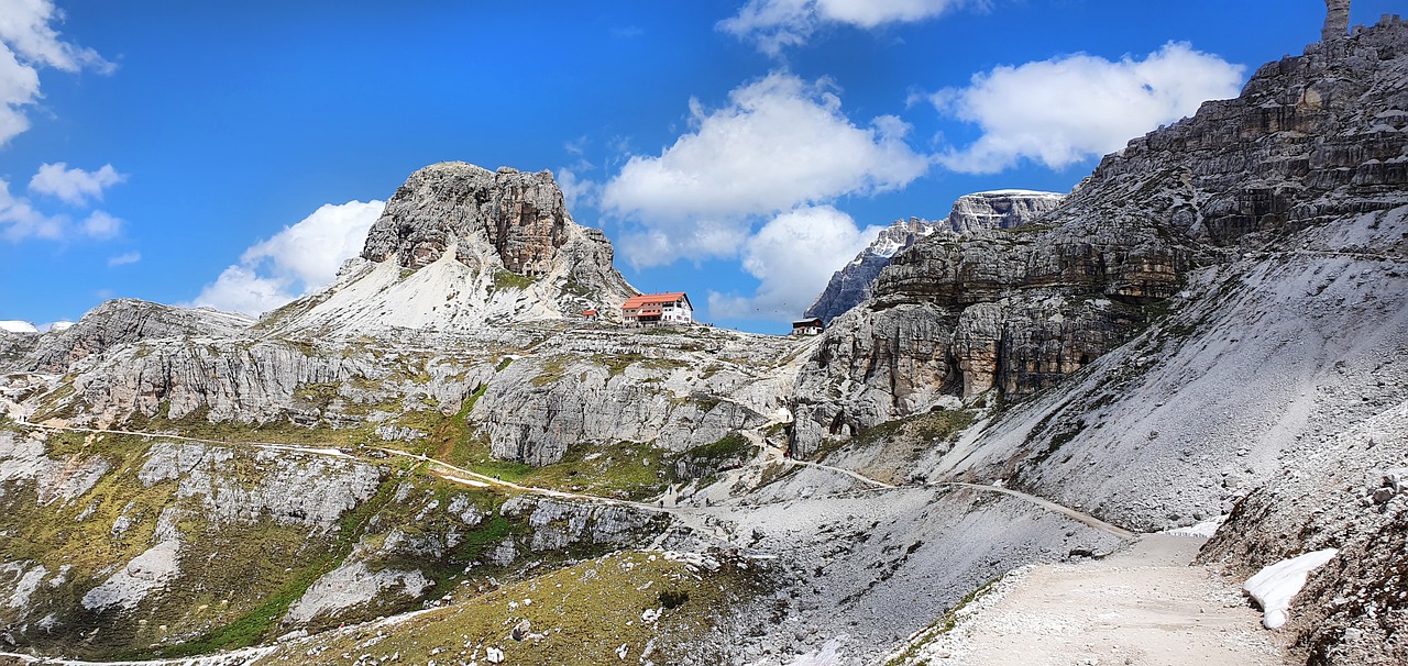 Sentiero di montagna con vista panoramica su vette e vallate italiane, immerso nella natura.