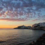 Borgo pugliese con vista panoramica su un tramonto mozzafiato sul mare.
