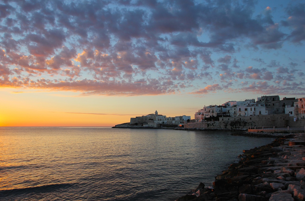 Borgo pugliese con vista panoramica su un tramonto mozzafiato sul mare.