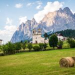 Vista panoramica del borgo nelle Dolomiti, circondato da montagne maestose e natura incontaminata.