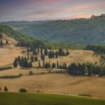 Paesaggio sereno della Toscana con colline verdi e cipressi, simbolo di pace e bellezza naturale.