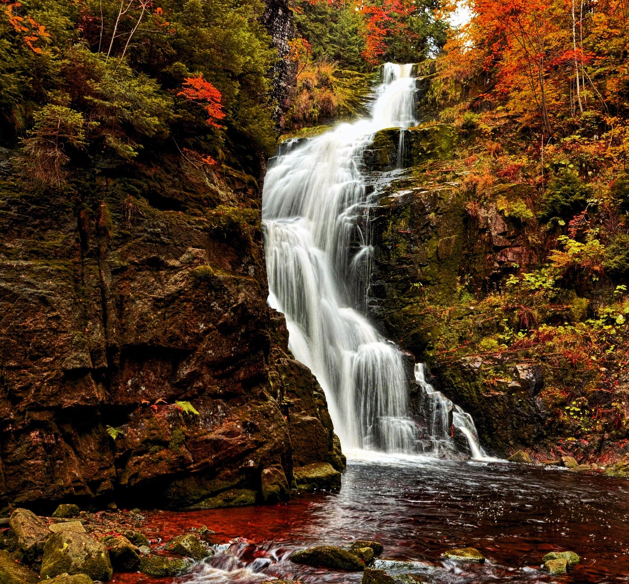 Cascate italiane immerse nei colori autunnali, circondate da foglie dorate e atmosfera serena.