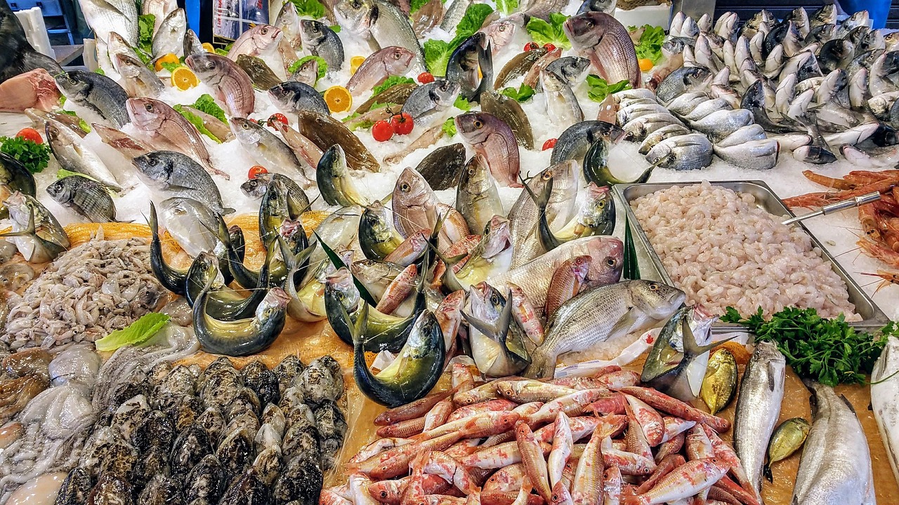 Mercato del pesce vivace in un borgo siciliano, con banchi colorati e specialità locali in esposizione.