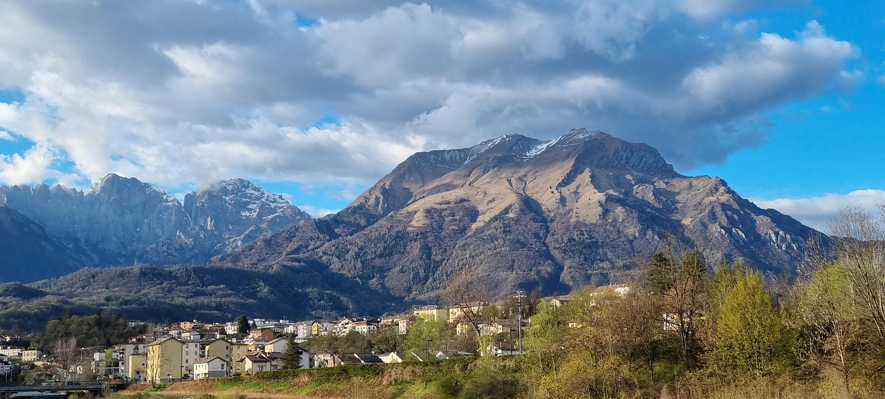 Panorama mozzafiato di una valle italiana nascosta tra le montagne, con verde intensi e un cielo azzurro.