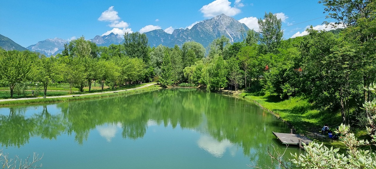 Lago del Trentino con acque turchesi, circondato da montagne verdi, ideale per una visita estiva.